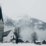 bird's-eye view photography of houses and cathedral near snow mountain